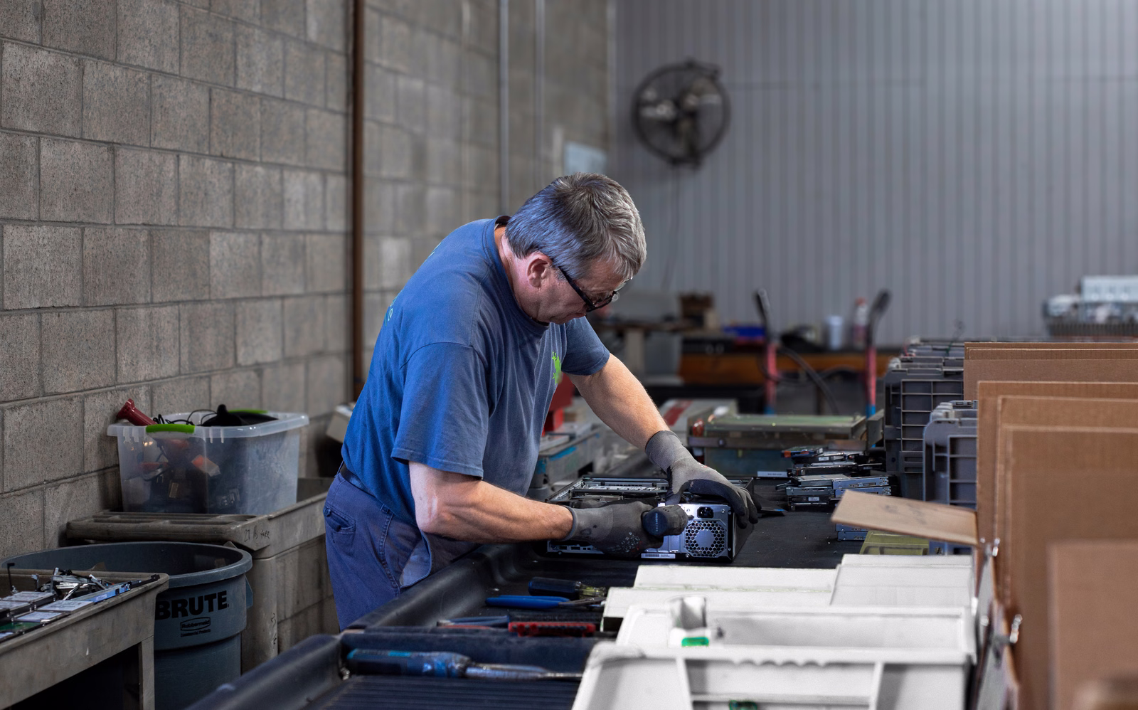 Technician disassembling computer components at a recycling facility workbench
