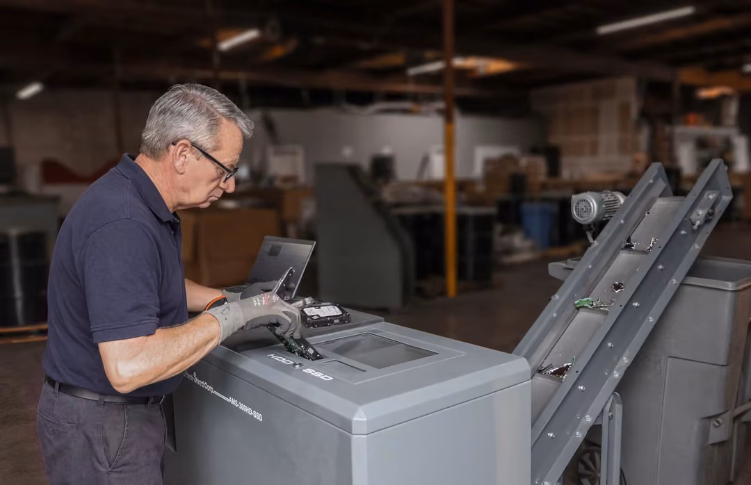Modern Waste Solutions technician feeding a hard drive into a hard drive and SSD shredder