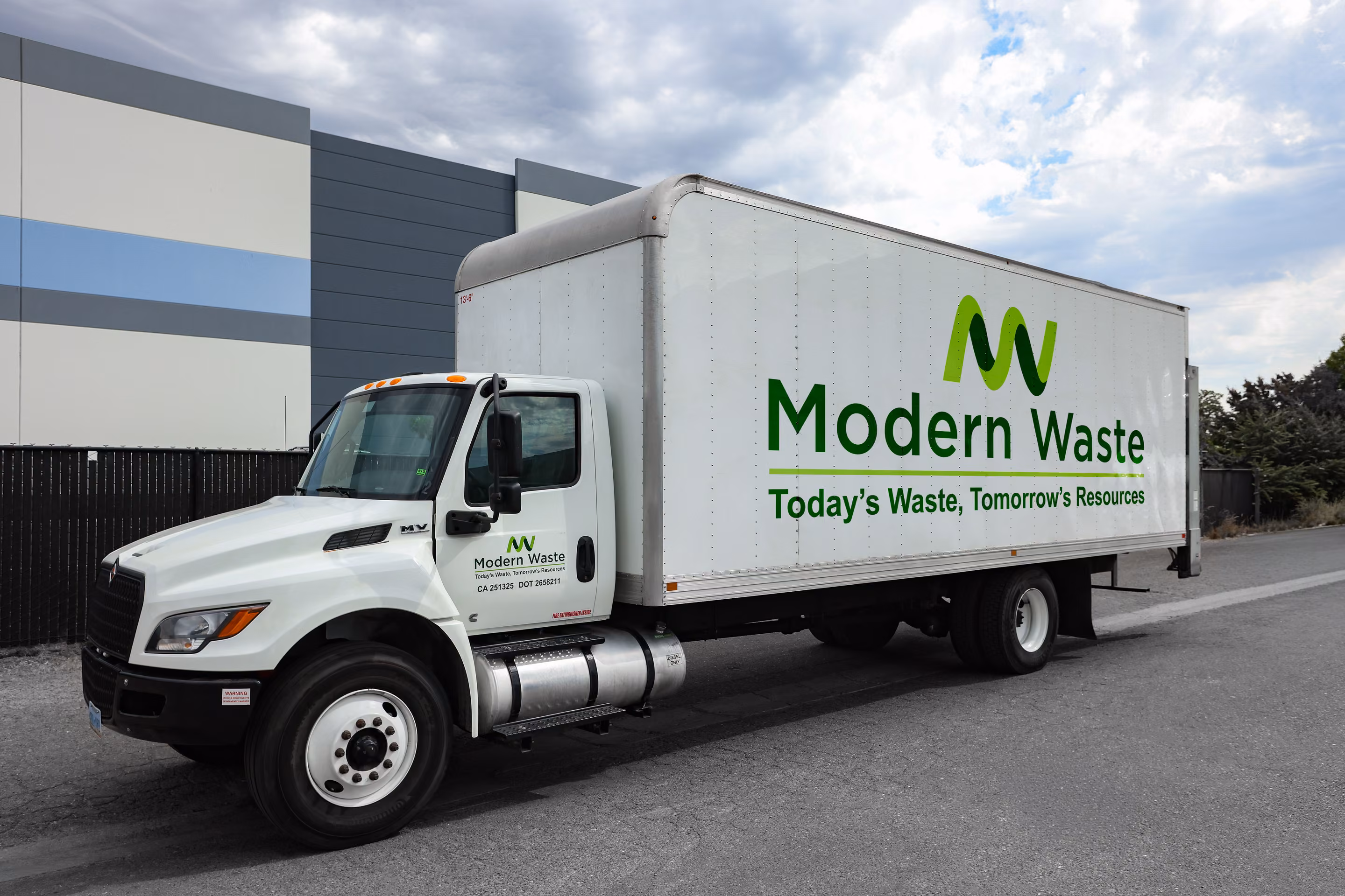 Modern Waste Solutions box truck parked at a commercial building for a pickup