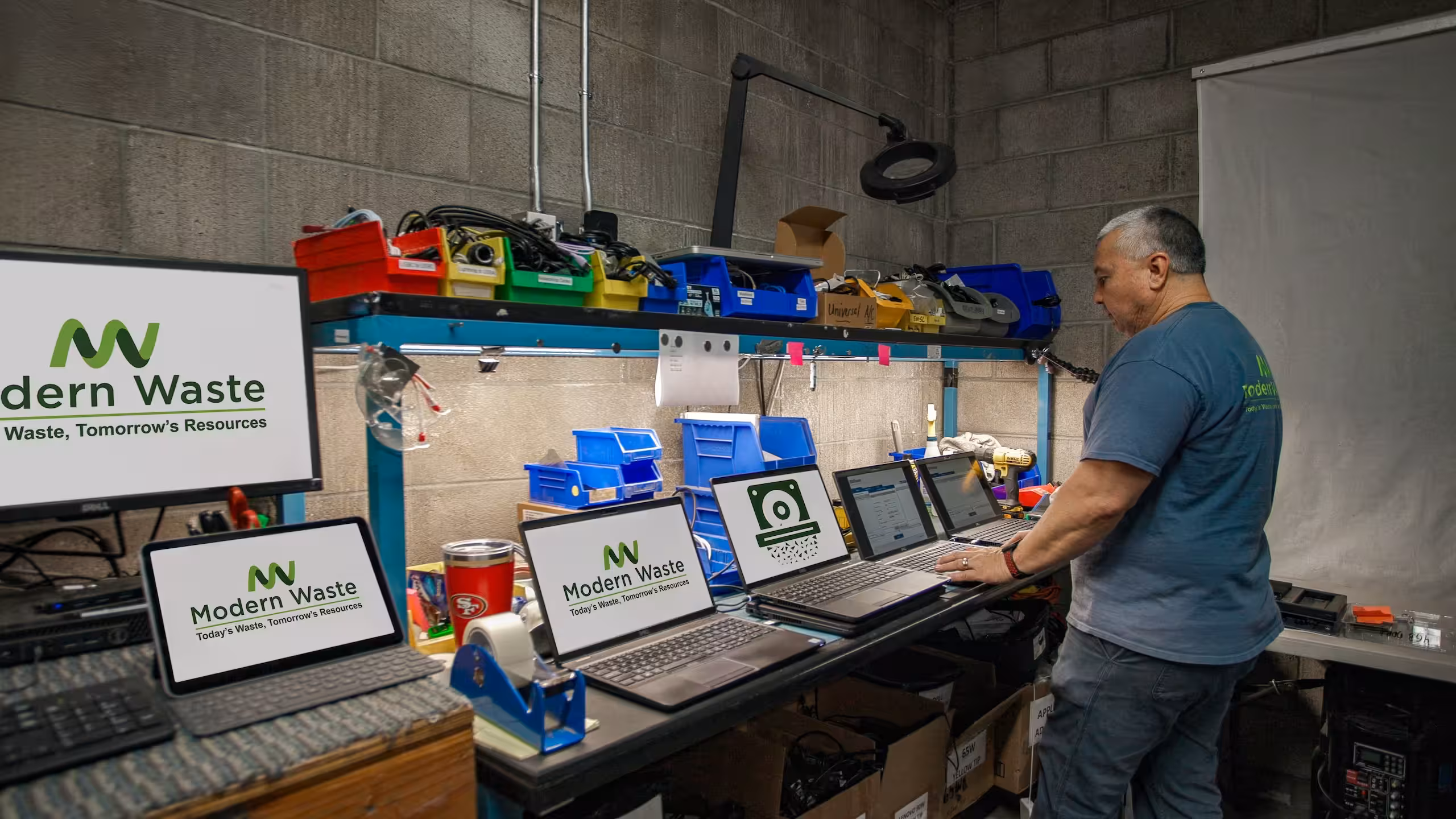 Modern Waste technician processing laptops and IT equipment at a workstation